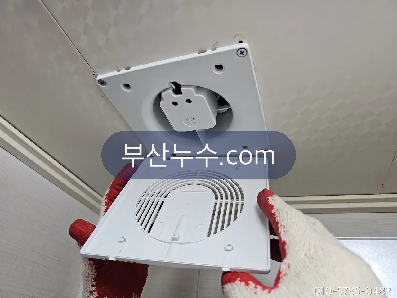아래층 화장실 천장 환풍기 패널을 열어 위층 배관을 살피는 장면