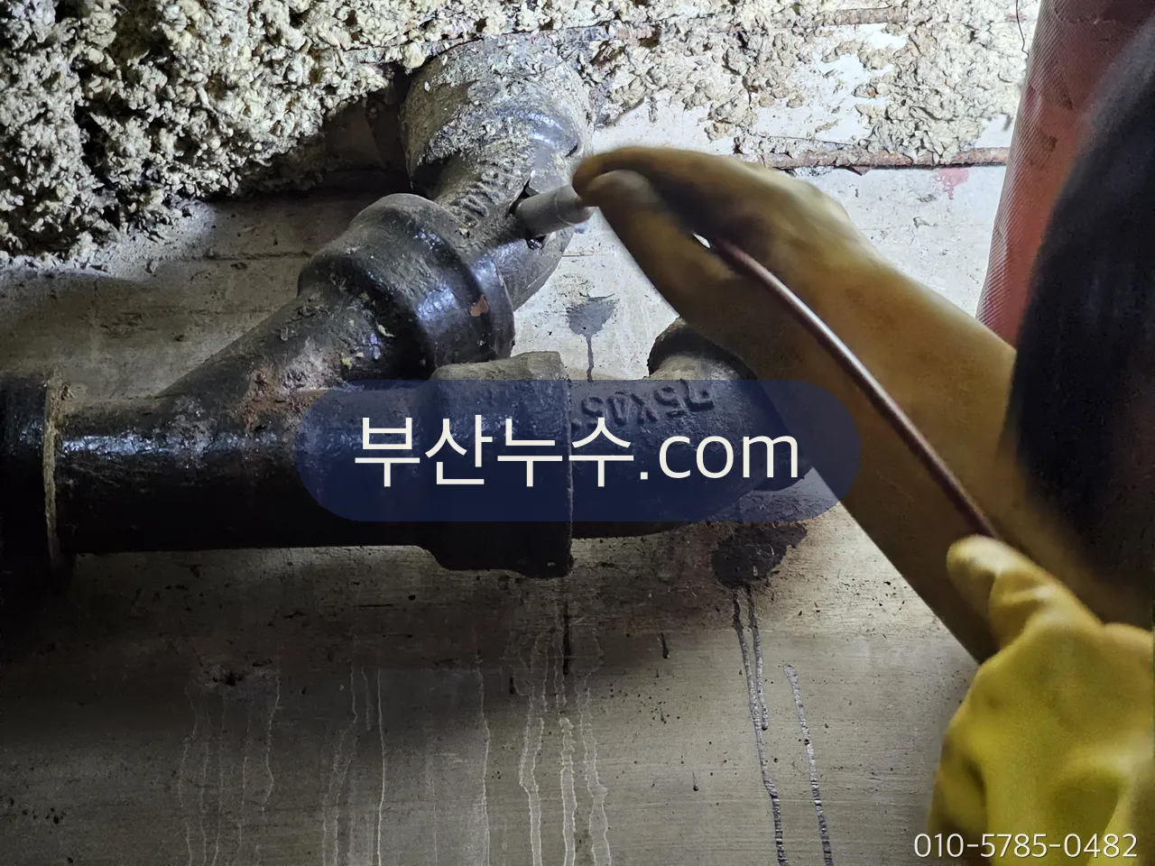 배관 밸브를 장갑 낀 손으로 잠그는 장면